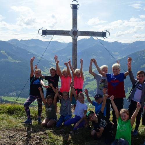 Kinder vor einem Gipfelkreuz