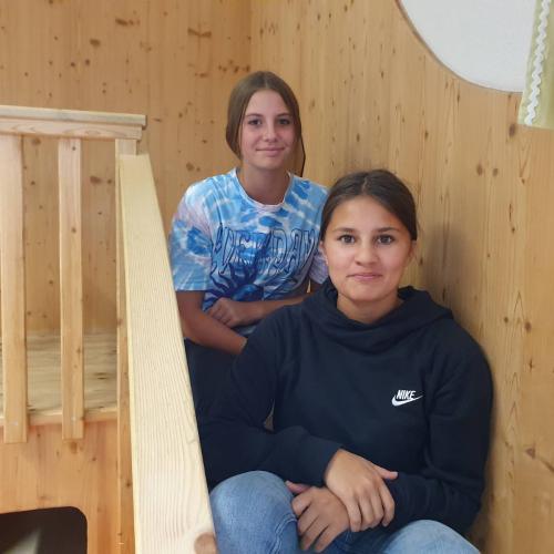 Zwei Mädchen sitzen auf einer Holztreppe