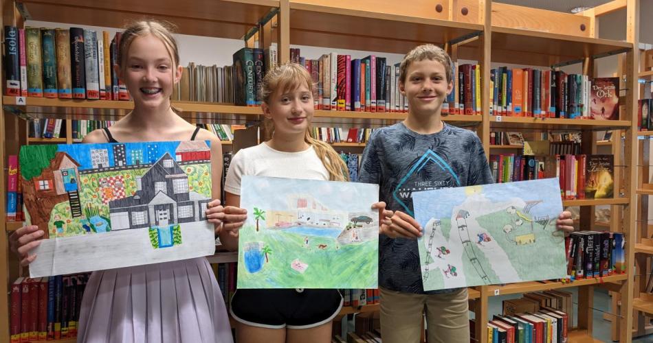 Drei Kinder präsentieren ihre Zeichnungen
